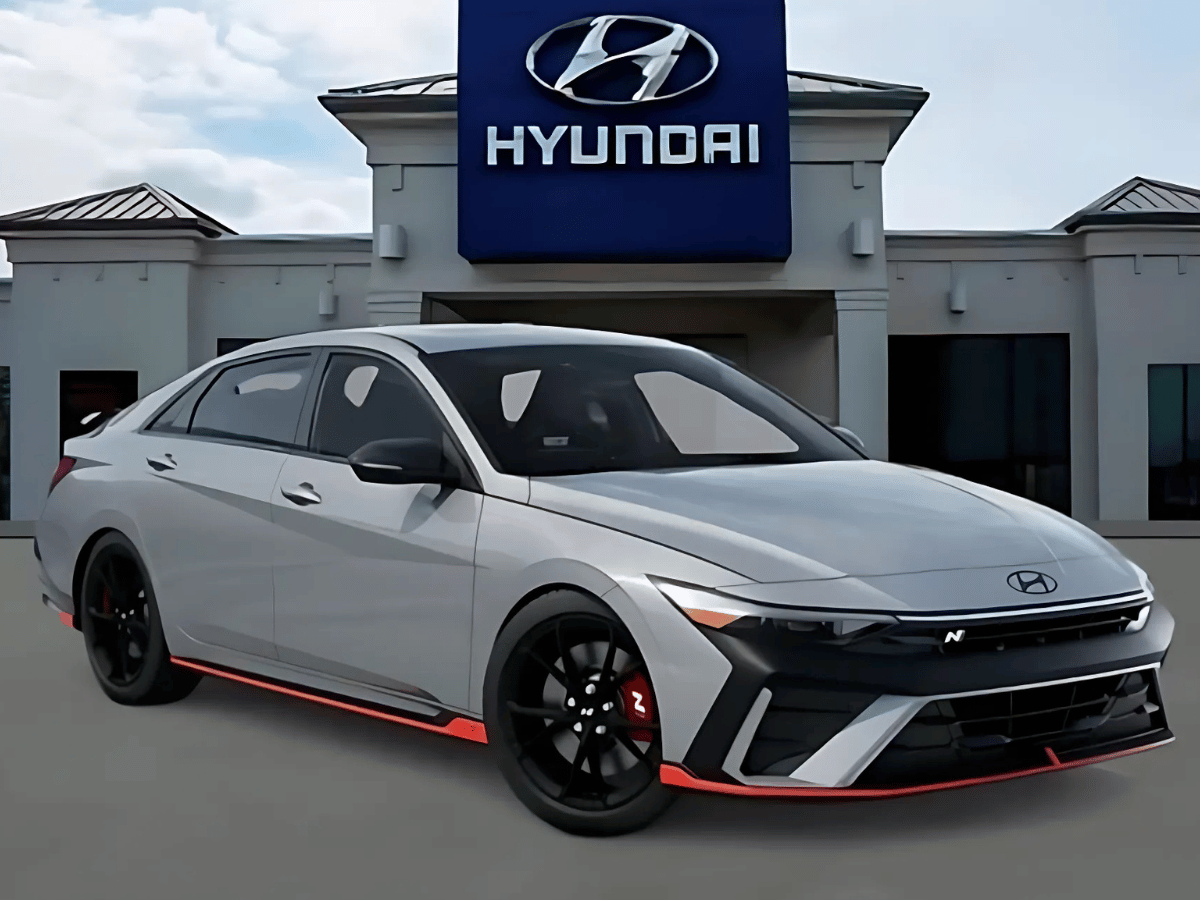 2025 Hyundai Elantra N trim in front of Crain Hyundai of Bentonville showcasing sporty design and black alloy wheels
